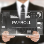 The images mentions Payroll outsourcing for businesses. There ia man in black suit holding a pc with screen depicting payroll.