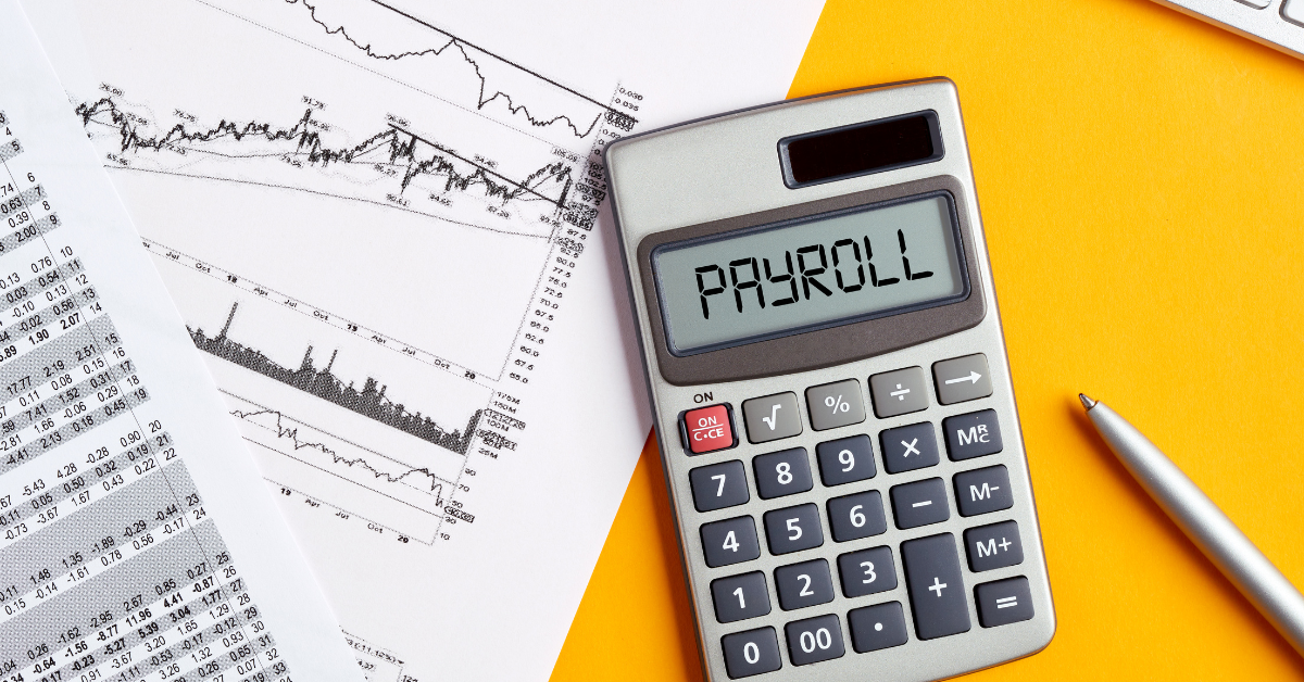 The image has yellow desk with lest side showcasing two papers with graphs with a calculator slightly on top of documents. The calculator shows payroll. Overall, the image depicts the cost of outsourcing payroll services in singapore.